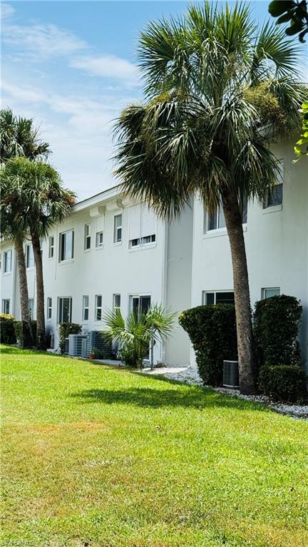 White stucco exterior with multiple windows, sliding glass doors, and mature palm trees
