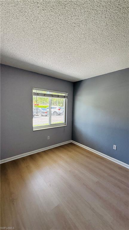 Wood-finish flooring, textured ceiling, and a window with blinds