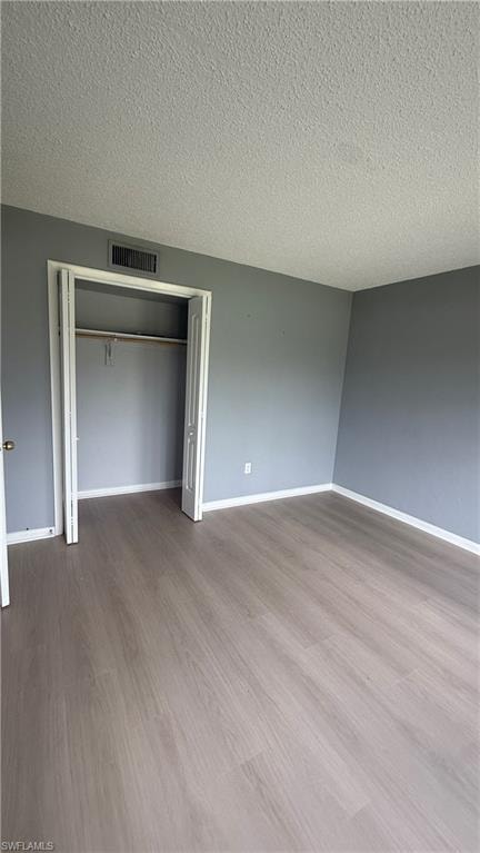 Spacious bedroom featuring wood-finish flooring, fresh neutral wall paint, and a large closet with bi-fold doors