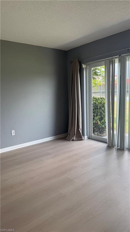 Light wood-finish flooring, gray wall paint, white baseboards, and sliding glass doors