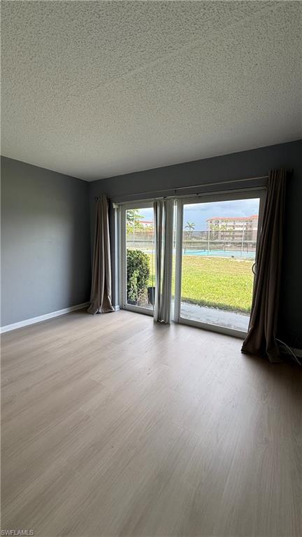 Wood-finish flooring with a smooth finish, sliding glass door, and a grassy outdoor area