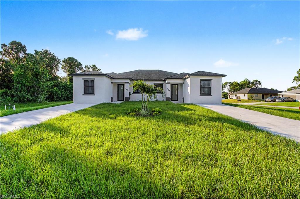 Contemporary duplex property featuring a stucco exterior, dark roof, and distinct entryways