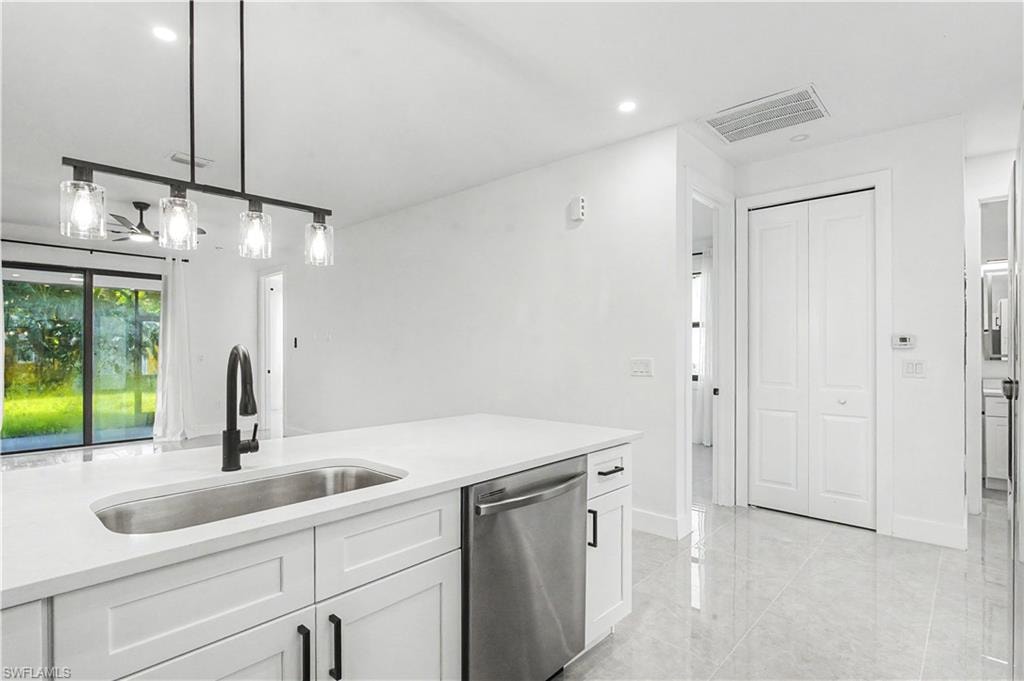 Modern kitchen featuring clean-lined white cabinetry, a stainless steel undermount sink with matte black faucet, and a quartz countertop with waterfall edge detail