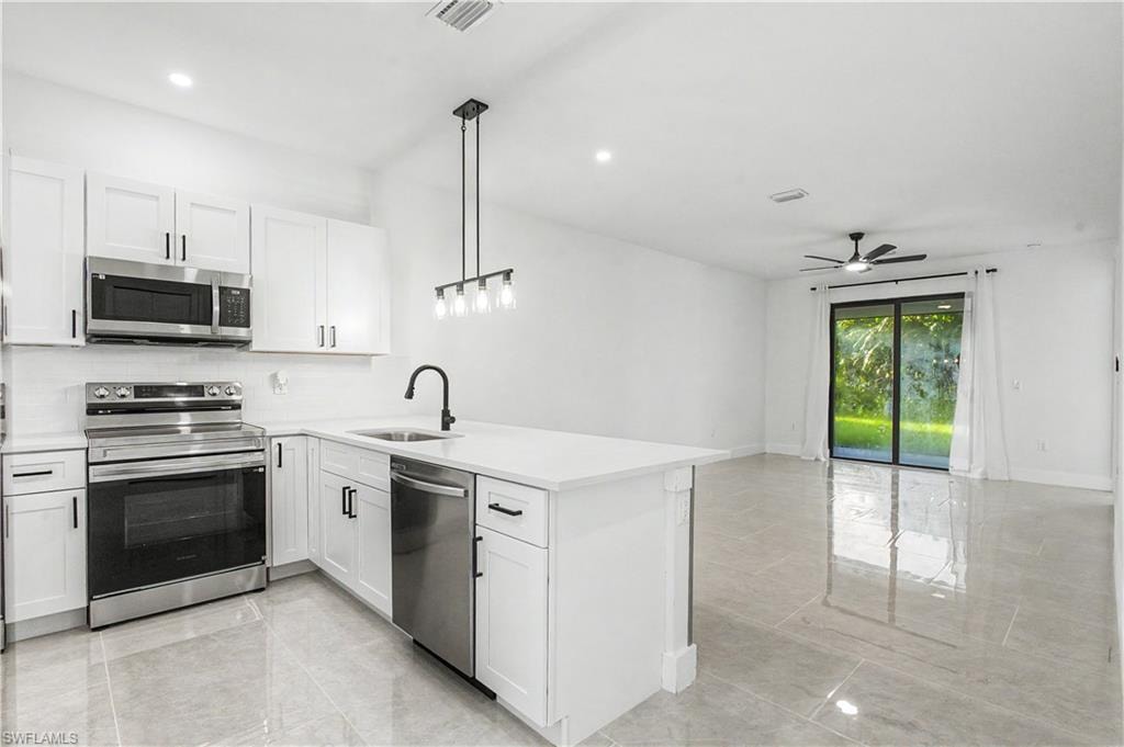 Modern kitchen featuring white shaker cabinetry, stainless steel appliances, a white island with an undermount sink, and a black faucet