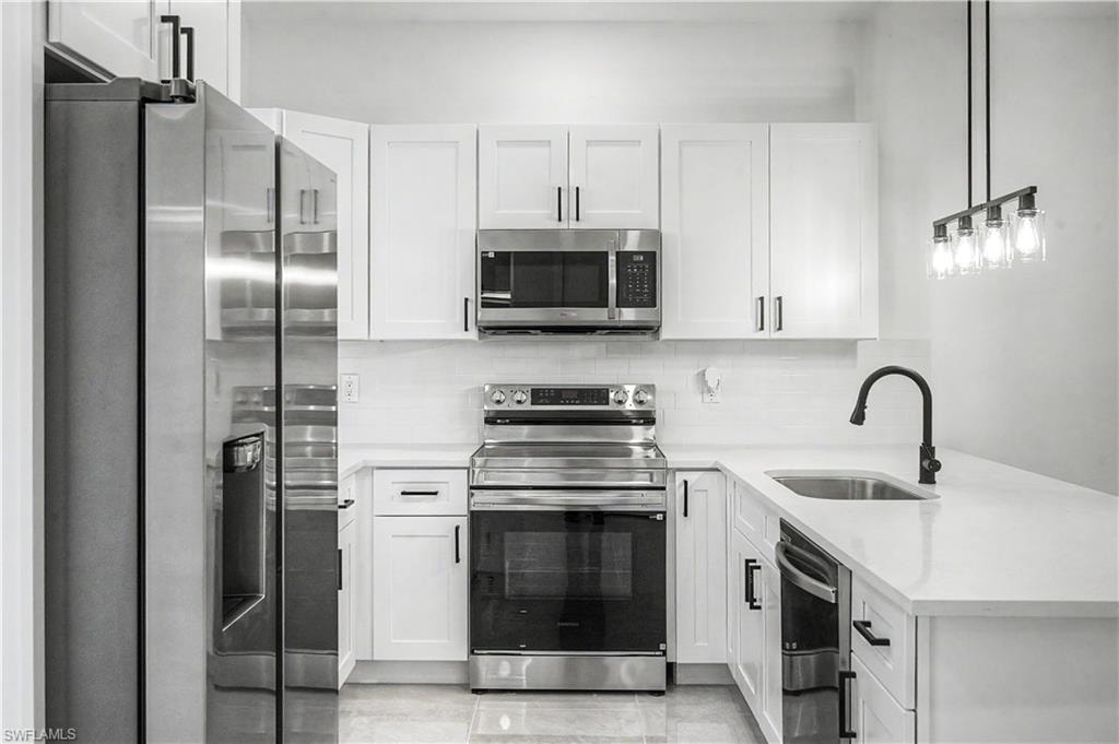 Bright kitchen featuring white shaker cabinetry, stainless steel appliances, white countertops, and a subway tile backsplash