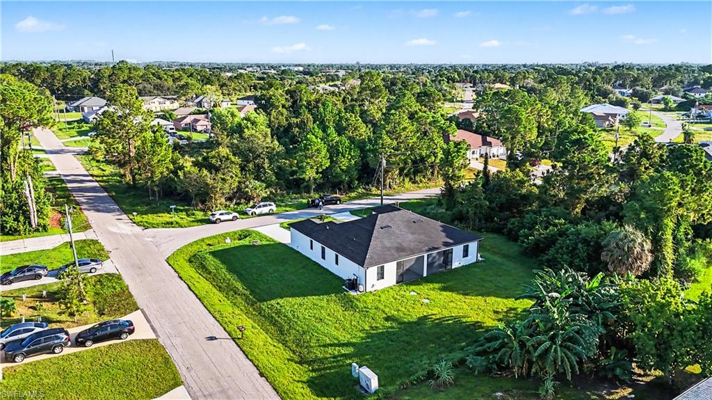 Modern single-story residence featuring a clean-lined white exterior with dark roof accents, situated on a spacious manicured lawn bordered by mature trees