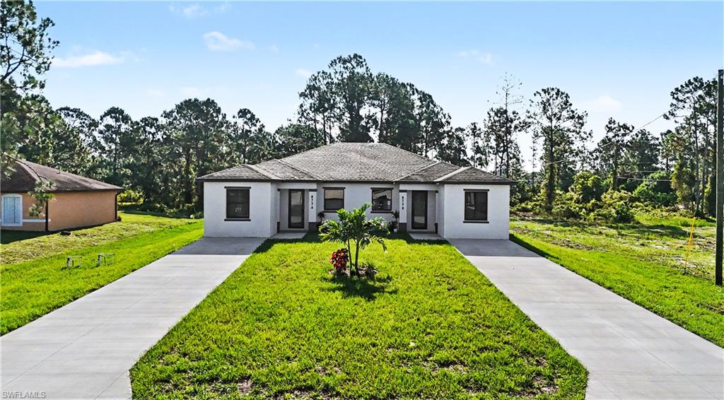 Modern duplex building featuring a light-colored stucco exterior, dark trim windows, and a shingle roof