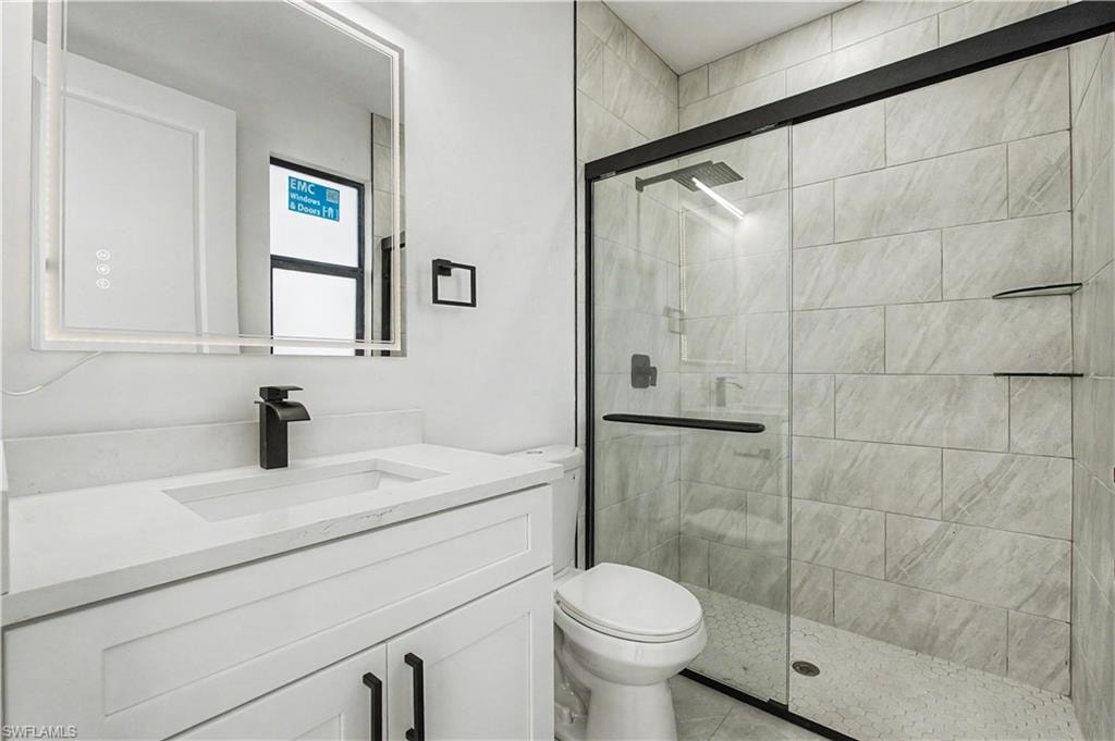 Contemporary bathroom featuring a white vanity with integrated sink, matte black faucet, and an illuminated mirror