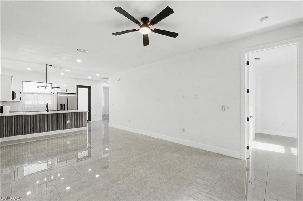 Open-concept living area featuring light gray tile flooring and a black ceiling fan with integrated lighting