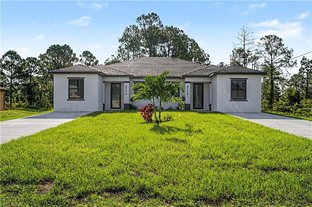 Duplex property featuring a stucco exterior and dark shingle roof