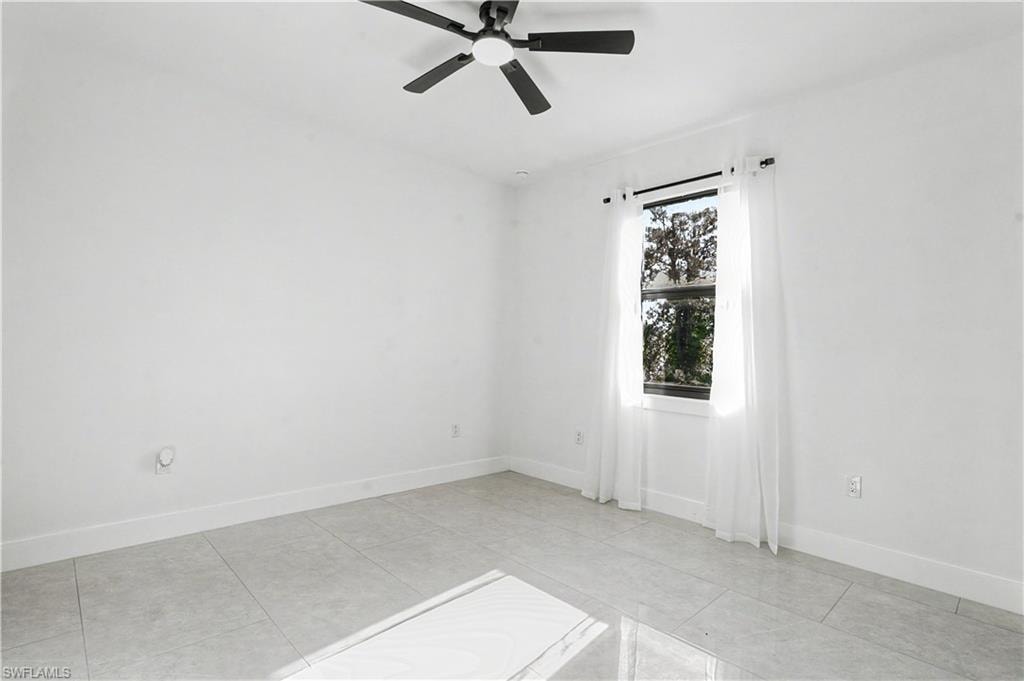 Room featuring light-colored tile flooring, white walls, and a window with a dark frame