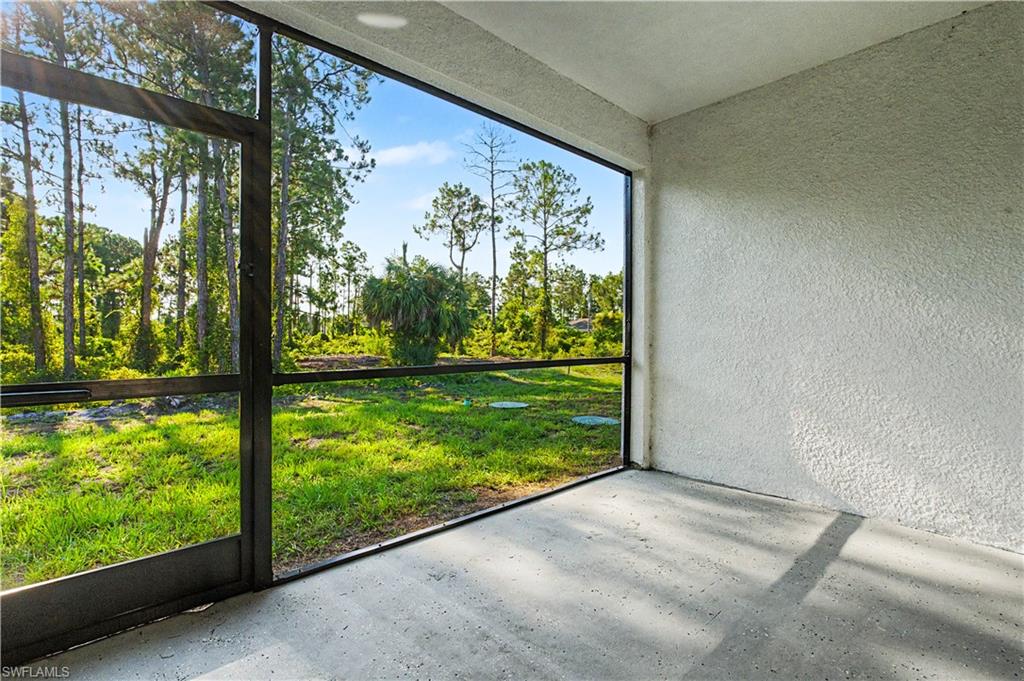 Screened patio featuring a concrete floor, textured stucco walls, and a clear view of the surrounding treeline and natural landscaping