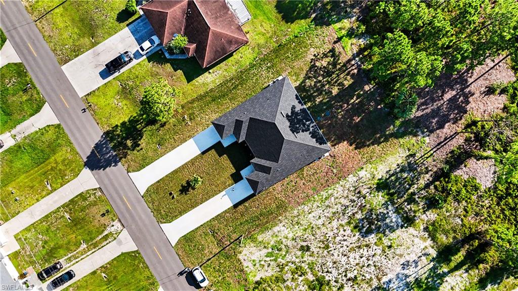 Newly constructed property featuring a dark shingle roof and a light-colored driveway