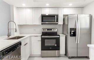 Kitchen featuring white cabinetry, light countertops, stainless steel appliances, a gooseneck faucet, and recessed lighting
