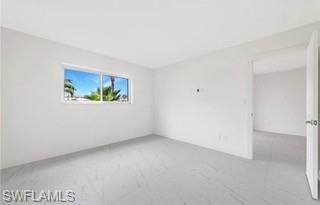 Bright room with large window, featuring white walls, light-toned flooring, and a white interior door