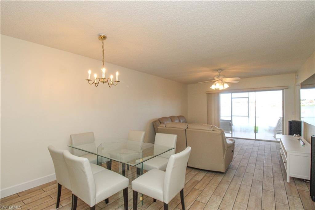 Dining space with a textured ceiling, ceiling fan with notable chandelier, and light hardwood / wood-style floors