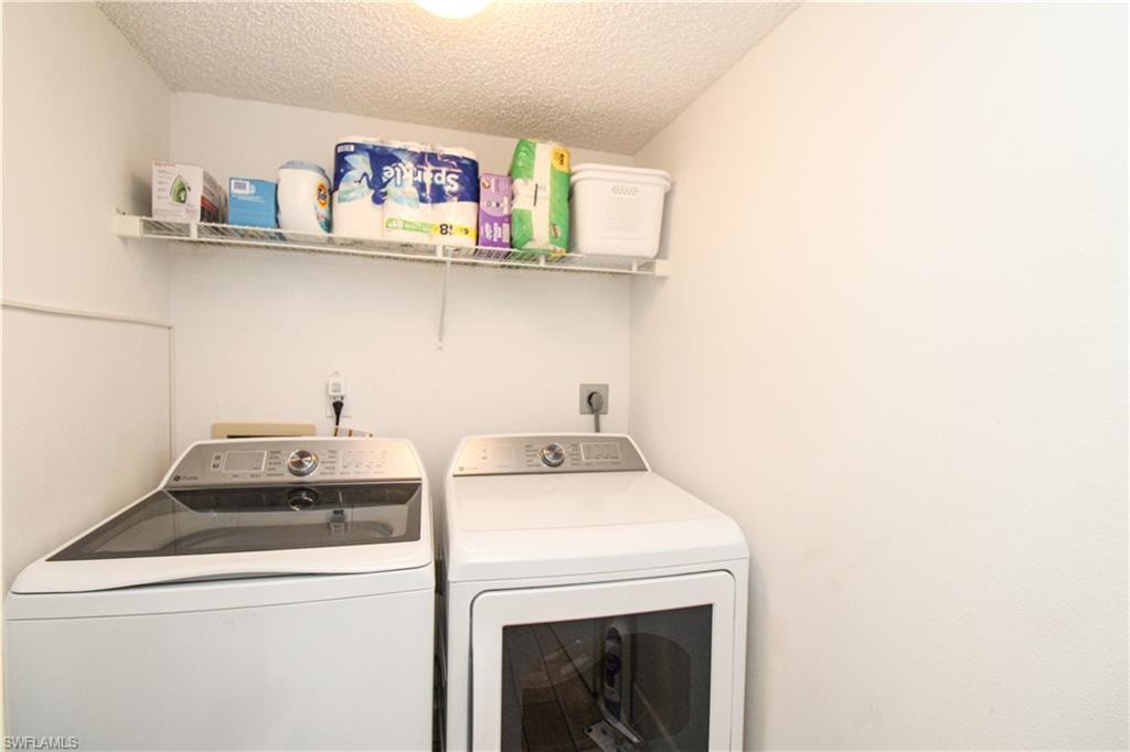 Washroom with a textured ceiling and washing machine and clothes dryer