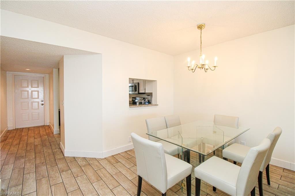 Dining space featuring a textured ceiling, an inviting chandelier, and light hardwood / wood-style flooring