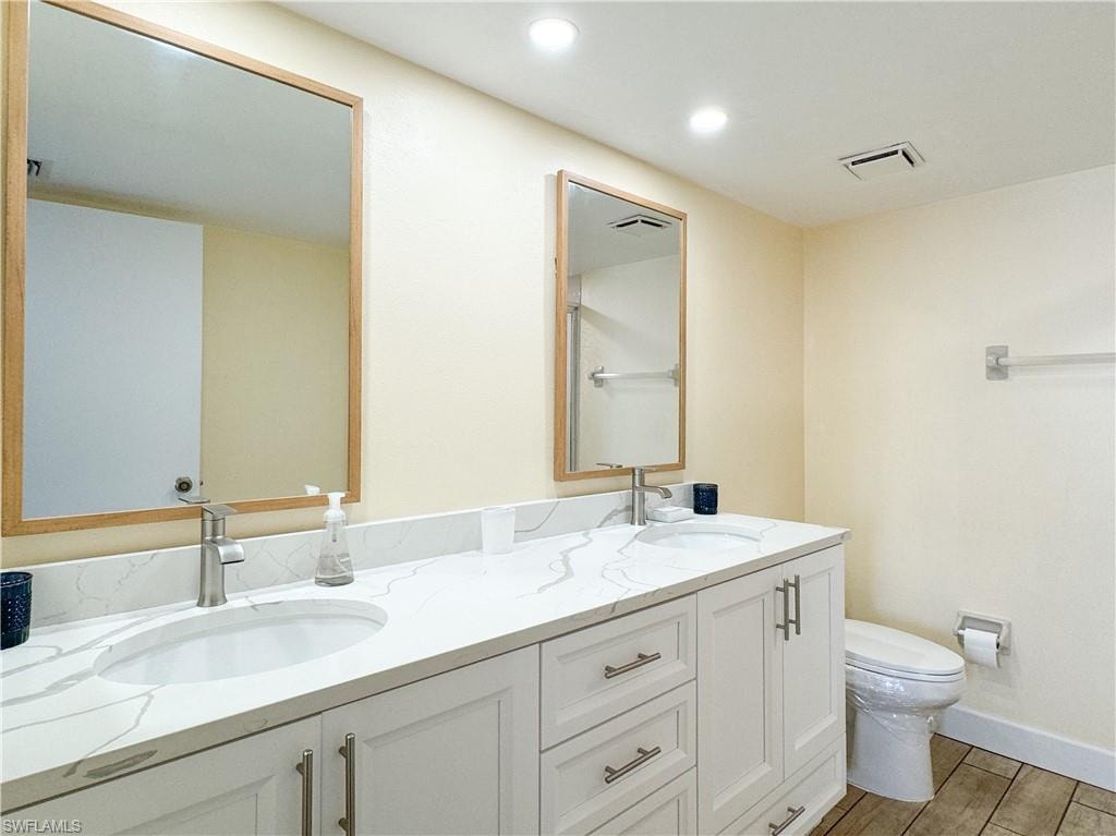 Bathroom with hardwood / wood-style floors, vanity, and toilet