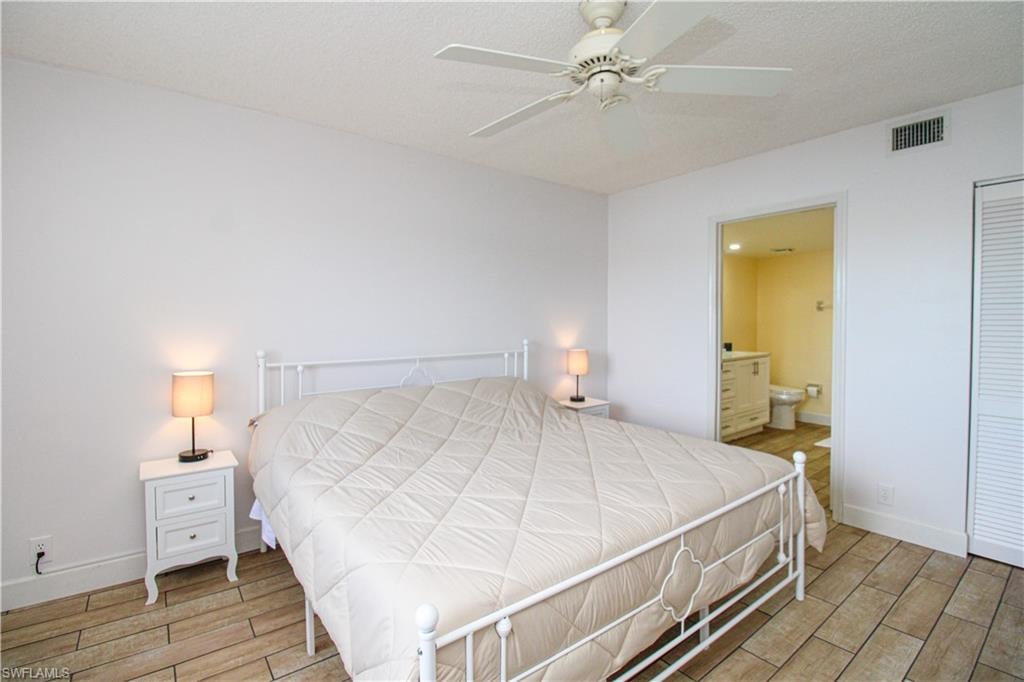 Bedroom featuring wood-type flooring, a closet, connected bathroom, and ceiling fan