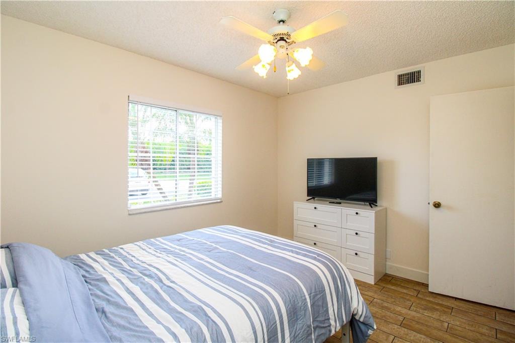 Bedroom with a textured ceiling, ceiling fan, and hardwood / wood-style flooring