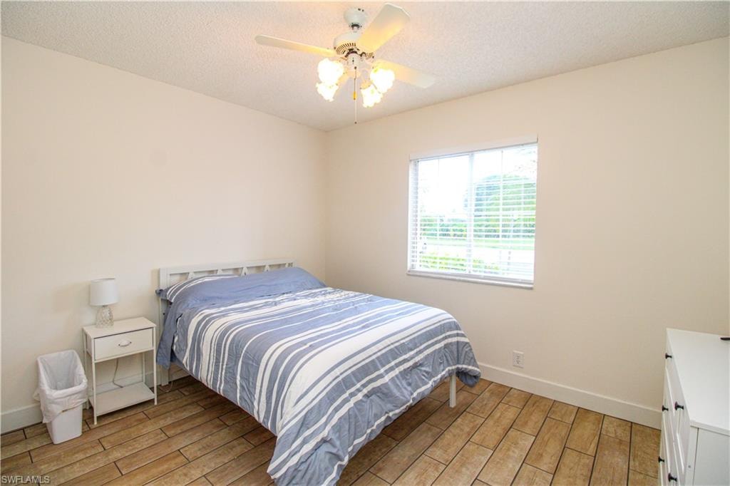 Bedroom with ceiling fan, a textured ceiling, and light wood-type flooring