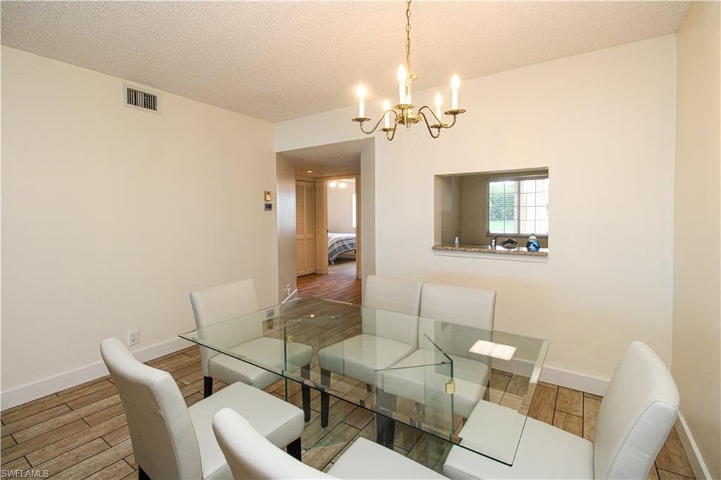 Dining space featuring a notable chandelier, a textured ceiling, and hardwood / wood-style flooring