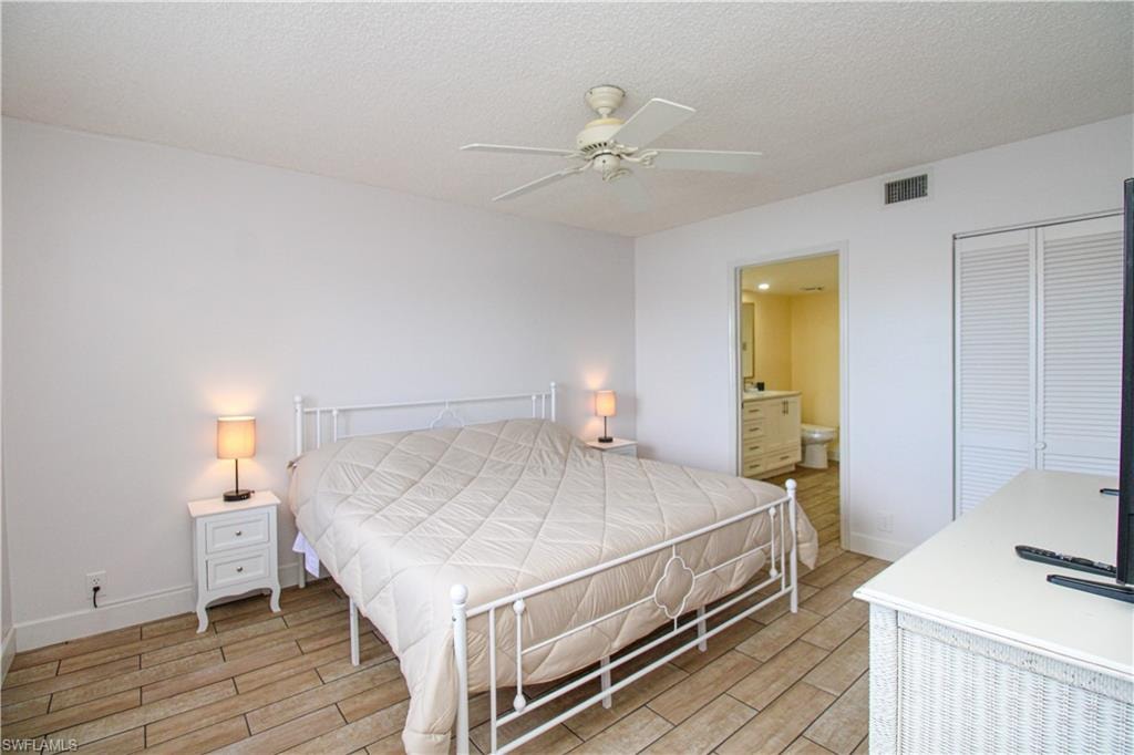Bedroom featuring connected bathroom, a closet, a textured ceiling, ceiling fan, and light hardwood / wood-style flooring