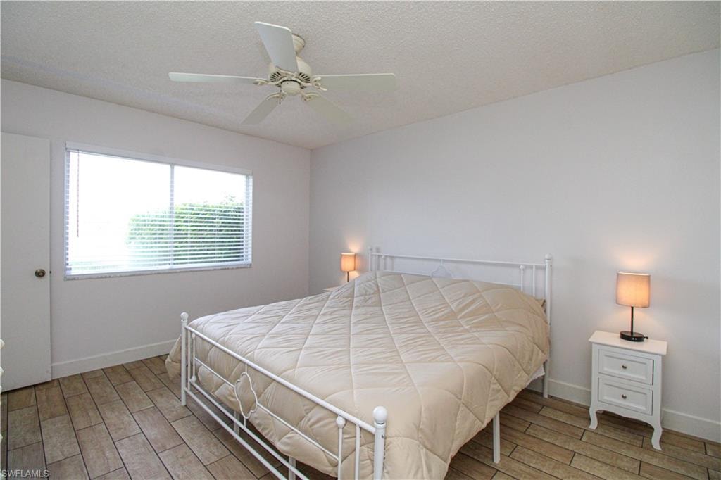 Bedroom with wood-type flooring, ceiling fan, and a textured ceiling