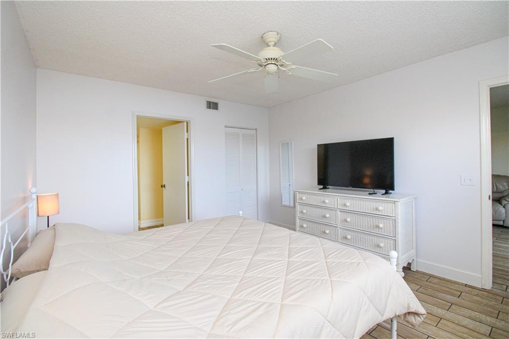 Bedroom featuring light wood-type flooring, a textured ceiling, ceiling fan, and a closet