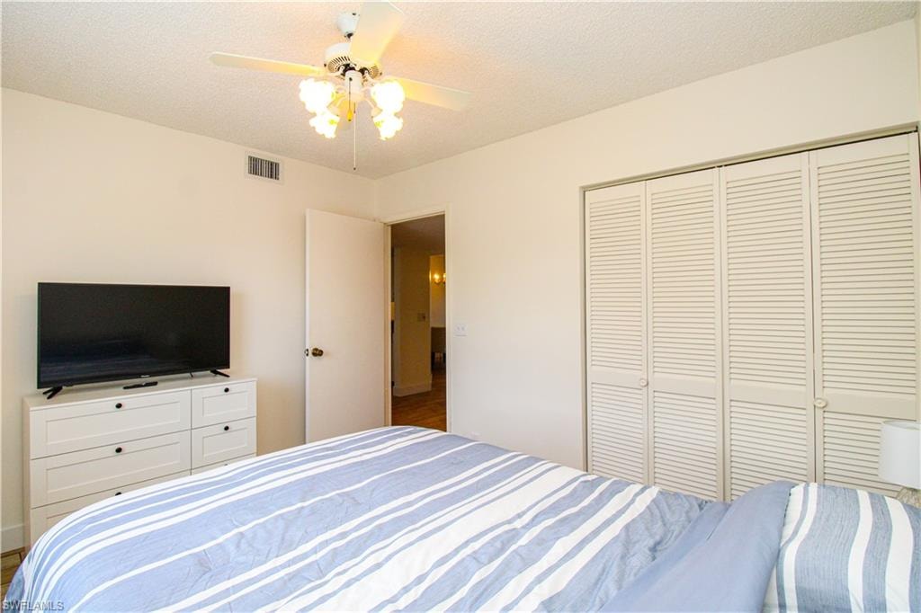 Bedroom with a closet, ceiling fan, and a textured ceiling