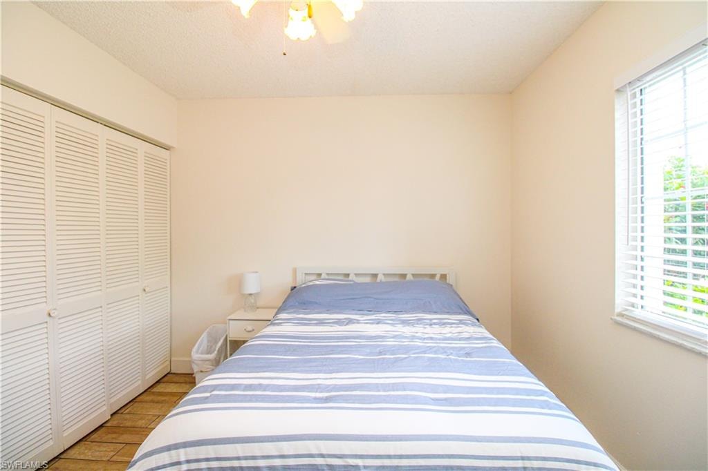 Bedroom with light hardwood / wood-style flooring, a closet, ceiling fan, and a textured ceiling