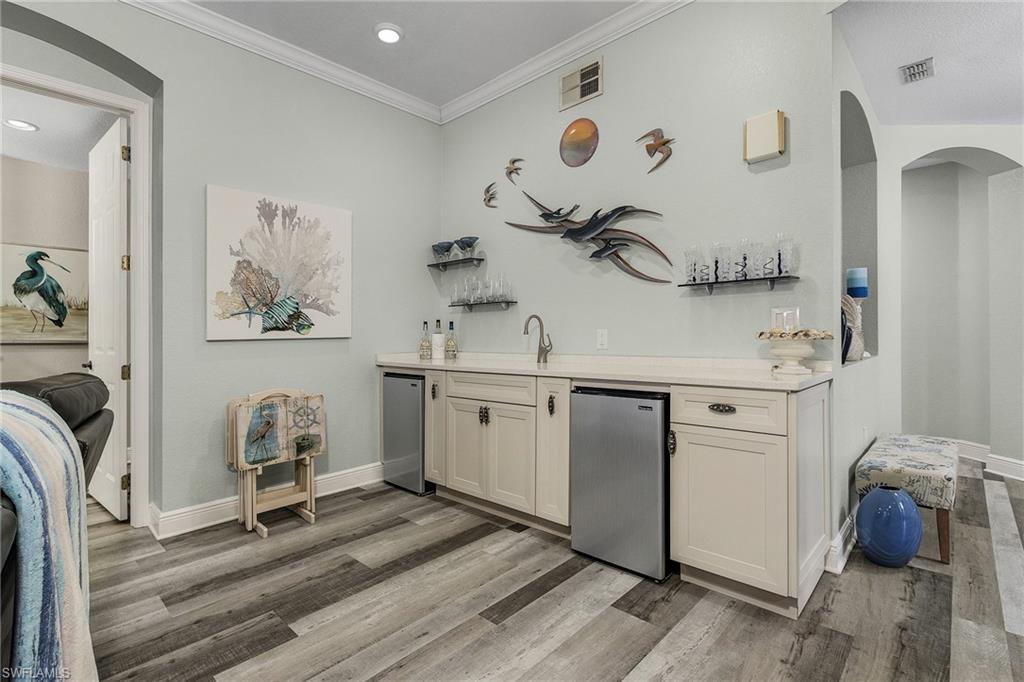 Bar with wet sink and refrigerators in living area for entertaining.