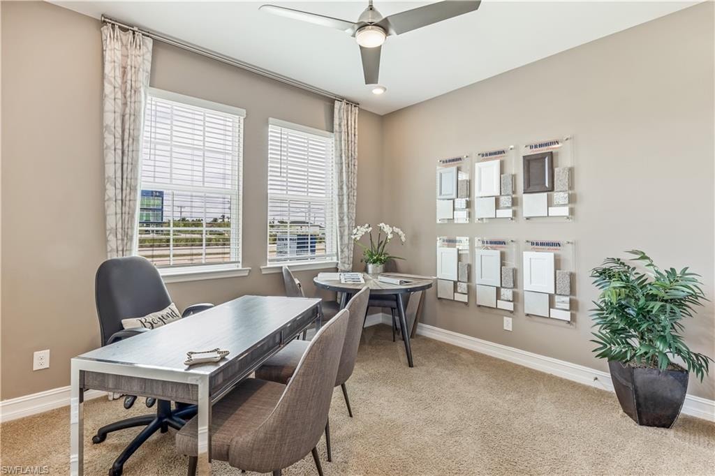 Sophisticated home office featuring a spacious desk with clean lines, comfortable seating for two, and abundant natural light from dual windows with plantation shutters and coordinating drapery