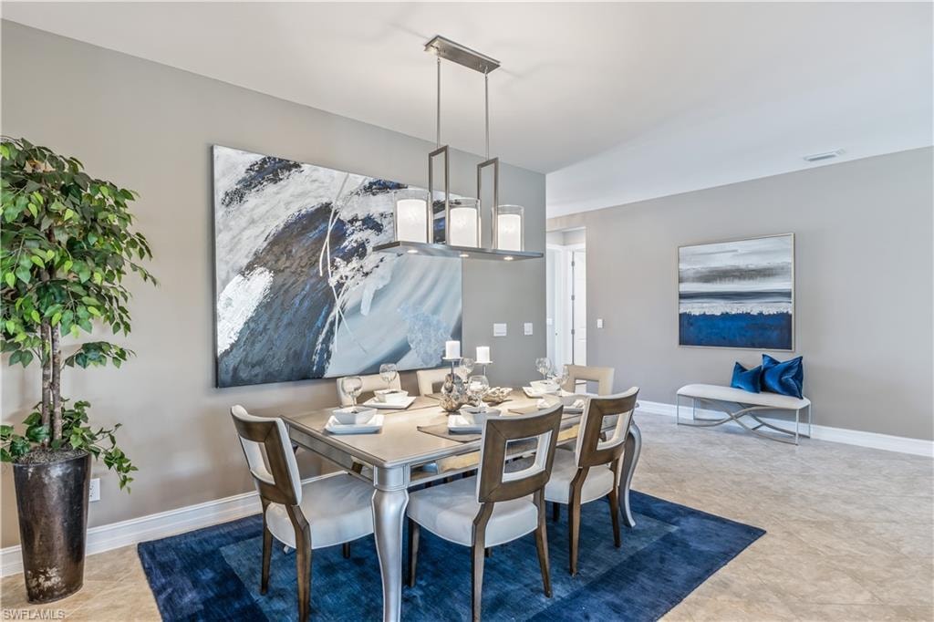 Formal dining area featuring a rectangular chandelier with frosted glass shades, light grey walls, and a recessed ceiling