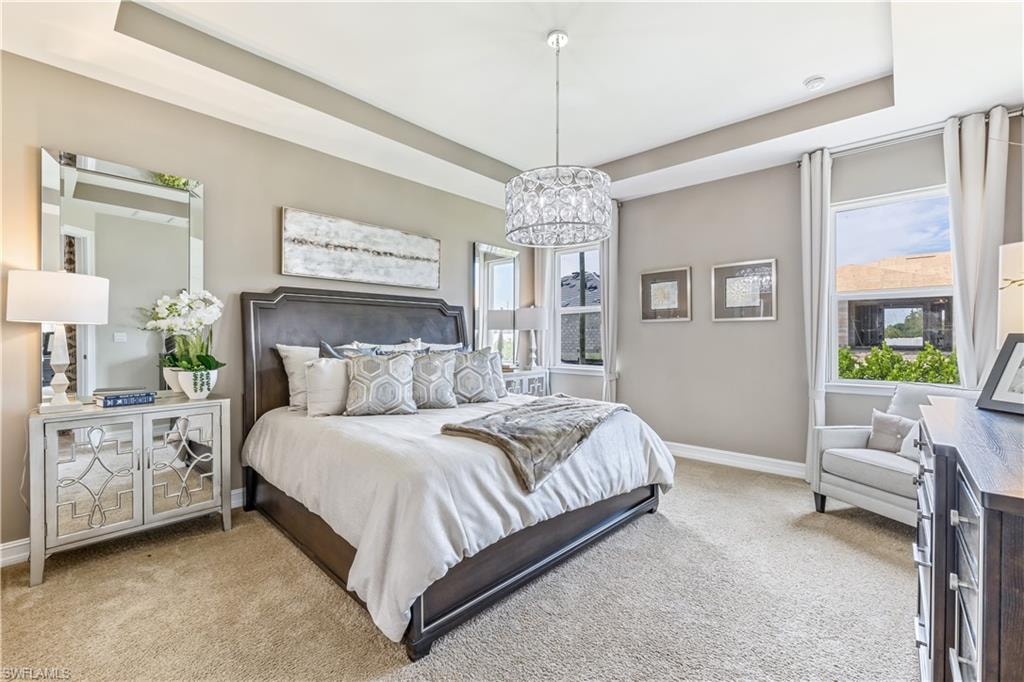 Luxurious primary bedroom featuring a upholstered platform bed with nailhead detailing, crystal pendant chandelier, and soft neutral palette