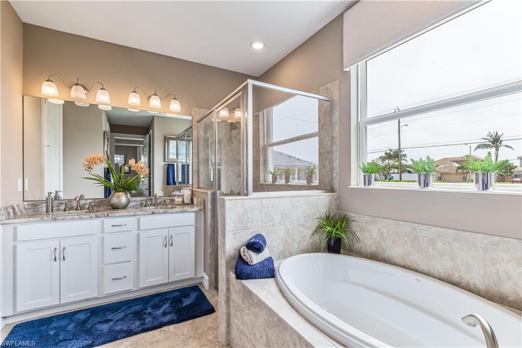 Spa-inspired primary bathroom featuring dual vanities with white cabinetry, polished nickel hardware, and an illuminated mirror