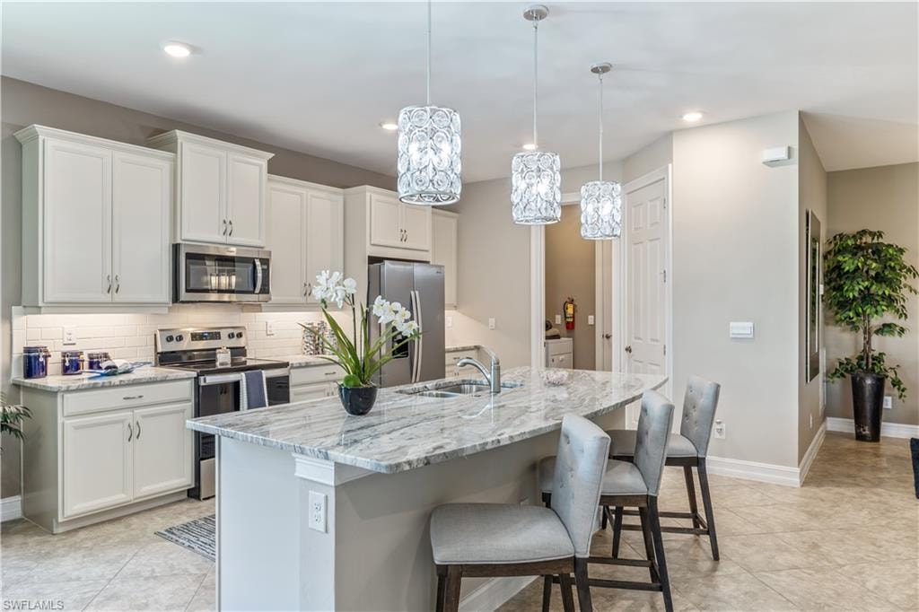 Modern kitchen and dining area featuring white shaker-style cabinetry, stainless steel appliances, and a large waterfall-edge island with seating for multiple guests