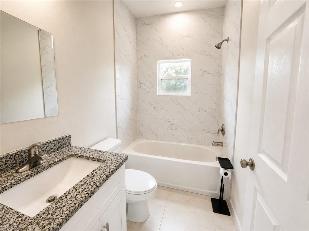 Bathroom featuring a white vanity with a speckled countertop, undermount sink, and brushed nickel faucet