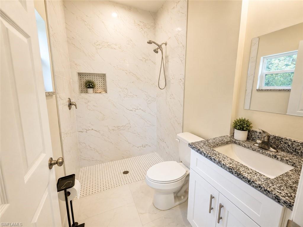 Shower with marble-look wall tile, integrated niche, and an open shower pan