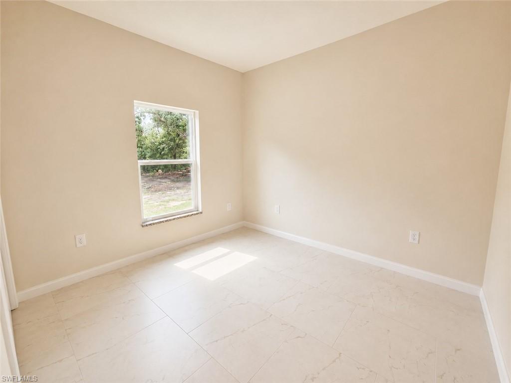 Neutral-toned interior room with light-colored tile flooring and a single window featuring a stone sill