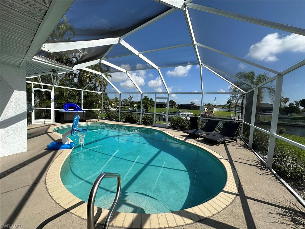 View of swimming pool featuring a patio area and glass enclosure