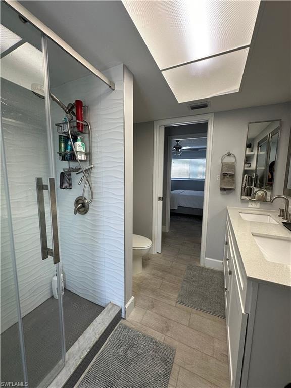 Bathroom with tile patterned flooring, double sink vanity, toilet, and an enclosed shower