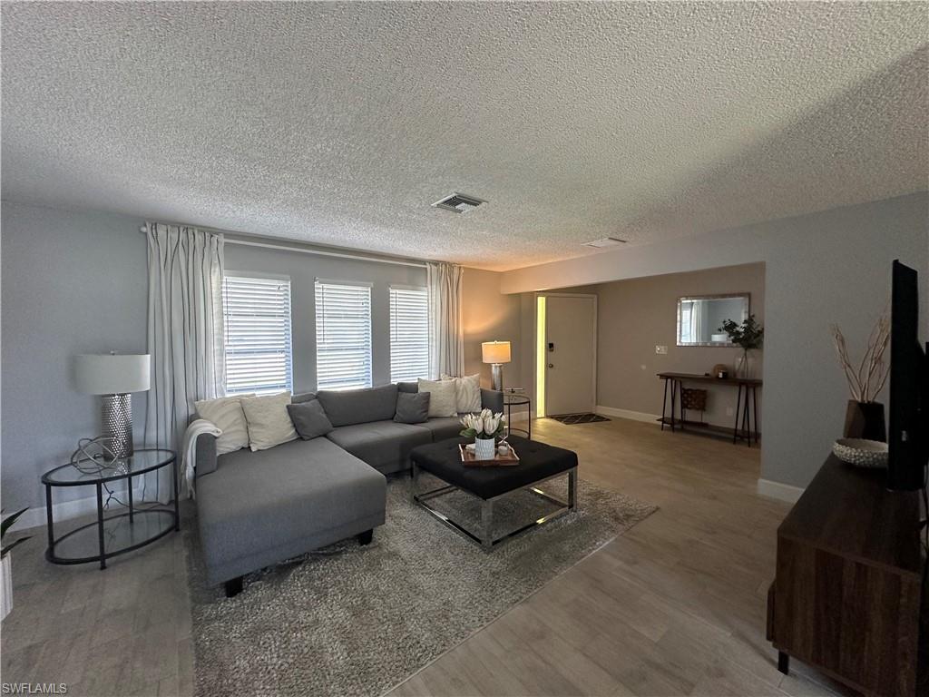 Living room featuring a textured ceiling and wood-type flooring