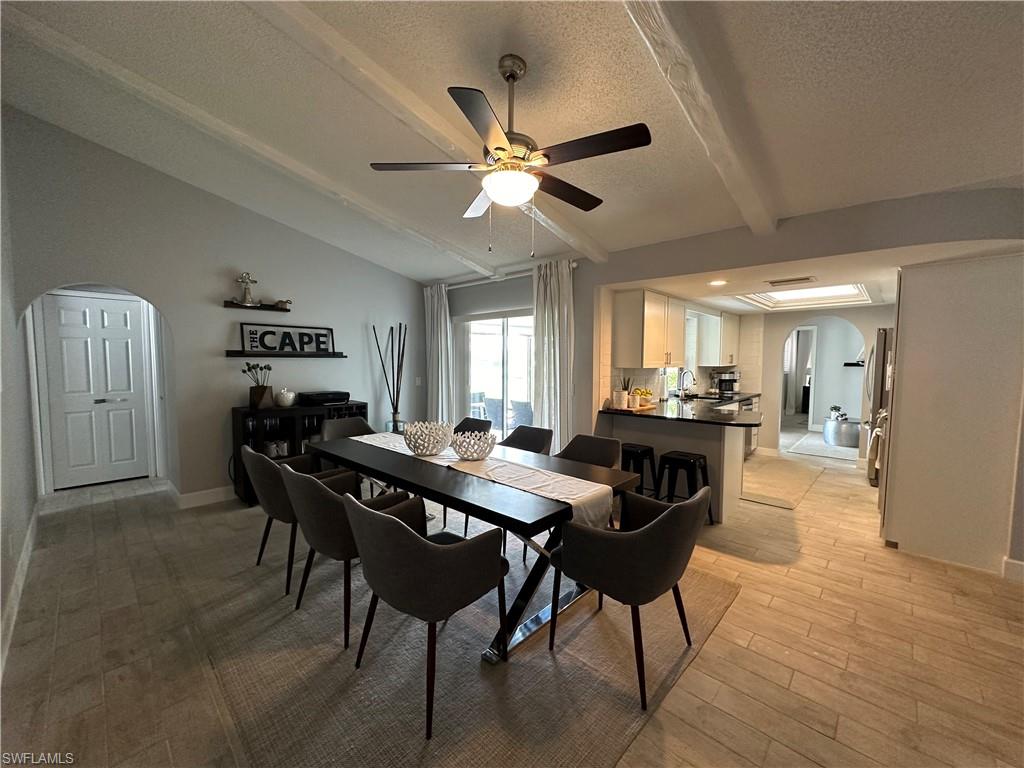 Dining room with lofted ceiling with beams, light hardwood / wood-style flooring, sink, a textured ceiling, and ceiling fan