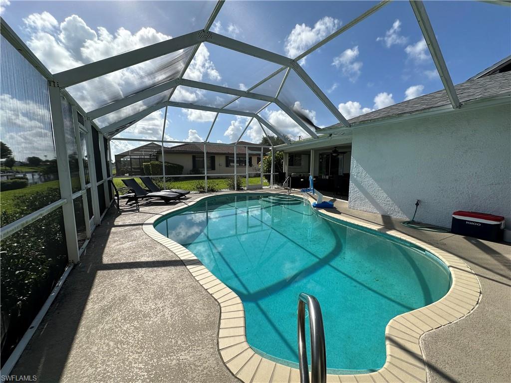 View of pool with a patio and glass enclosure