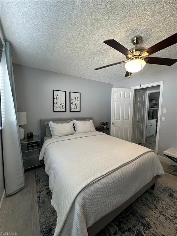 Bedroom featuring dark wood-type flooring, a textured ceiling, ceiling fan, and a closet