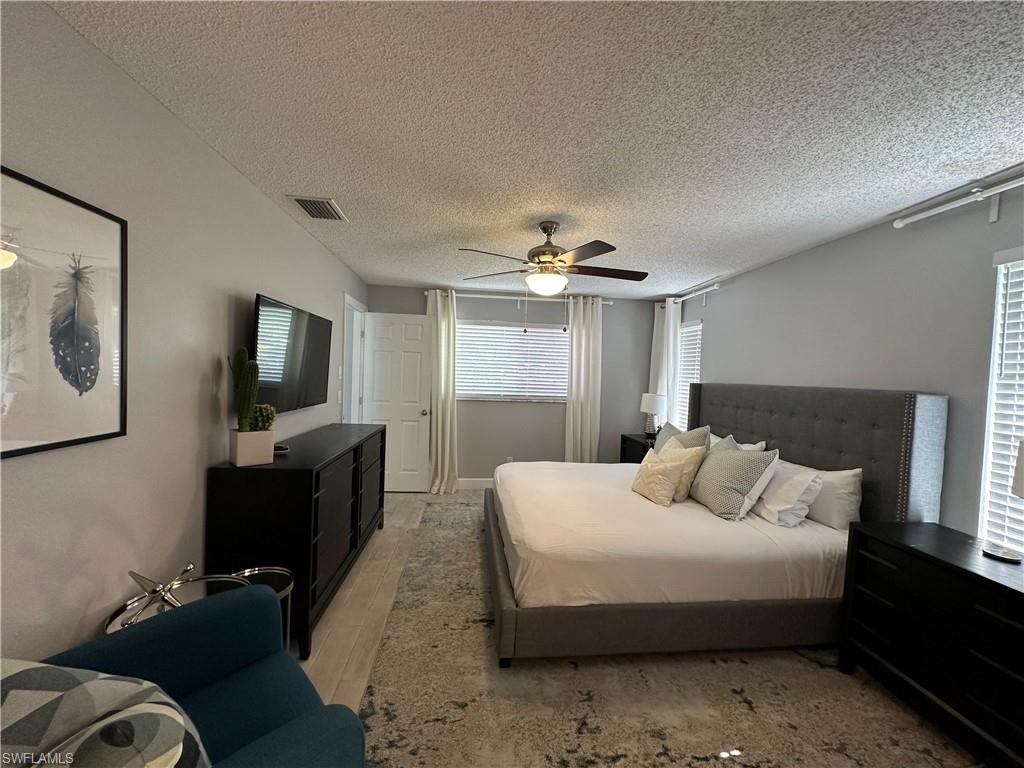 Bedroom featuring ceiling fan, wood-type flooring, and a textured ceiling
