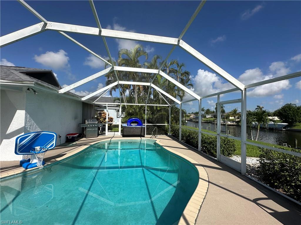 View of swimming pool featuring a patio, glass enclosure, and a water view