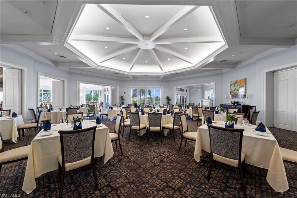 Spacious dining room featuring a coffered ceiling with recessed lighting, patterned carpet flooring, multiple sets of double doors, and broad window openings